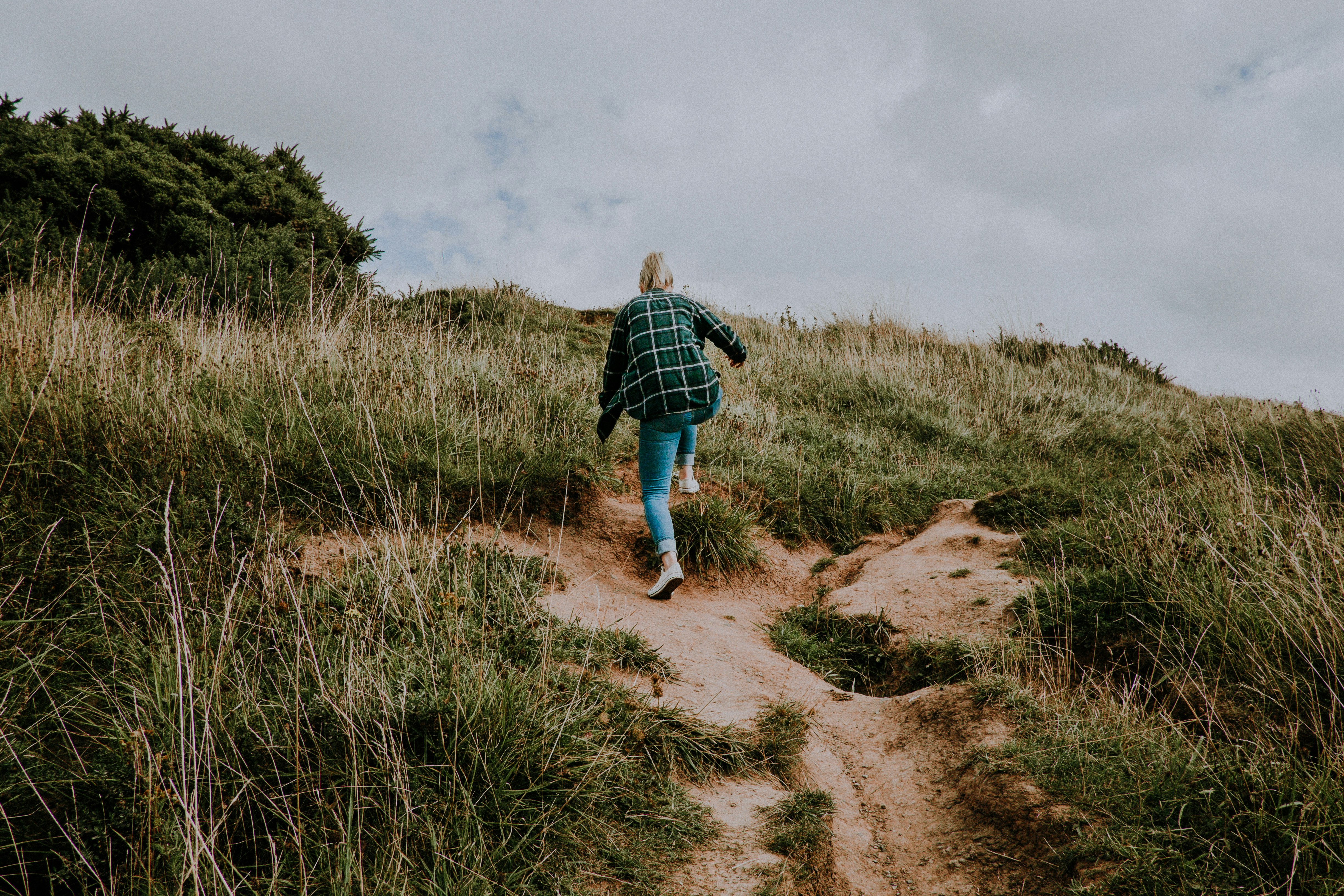 woman hiking on green mountain during daytime photo